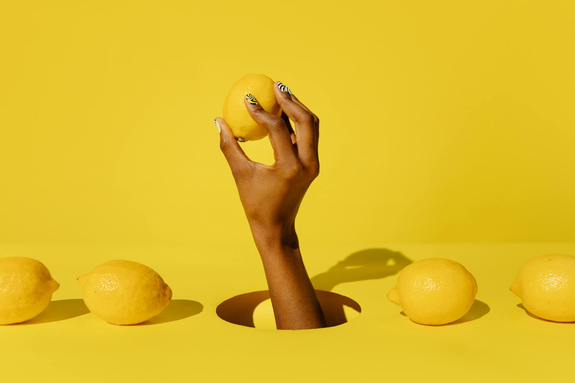 A hand holding a bright lemon against a vivid yellow background, symbolizing freshness and renewed pleasure in midlife