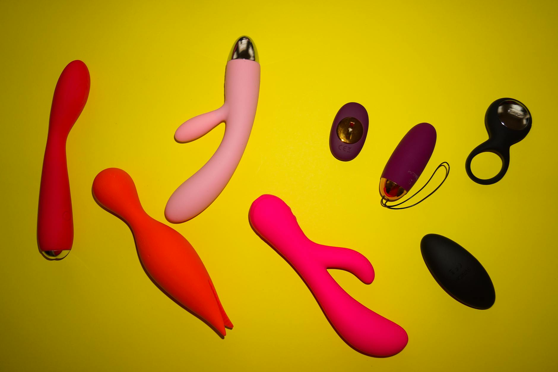 Variety of vibrators arranged on a bright yellow surface showing different designs